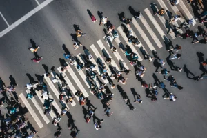 Different people at a pedestrian crossing in the city. People at a zebra pedestrian crossing - a lot of pedestrians in an overcrowded city on a sunny day. Aerial drone shot