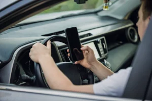 Young Man driving and looking message in his smart phone.