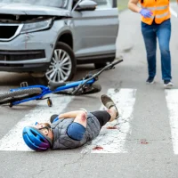 road-accident-with-injured-cyclist-lying-on-the-pedestrian-crossing-near-the-broken-bicycle-and-car-driver-running-on-the-background