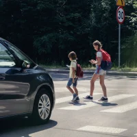 two-children-with-backpacks-cross-a-street-on-a-sunny-day