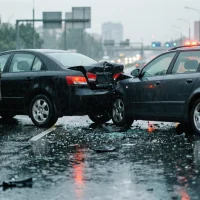 man-in-raincoat-standing-next-to-a-severe-car-accident-on-a-rainy-street